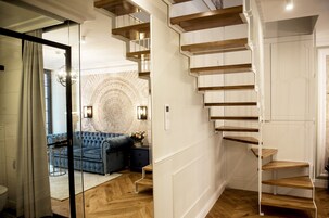 Un interior moderno con una escalera, un sofá azul y un papel tapiz estampado.