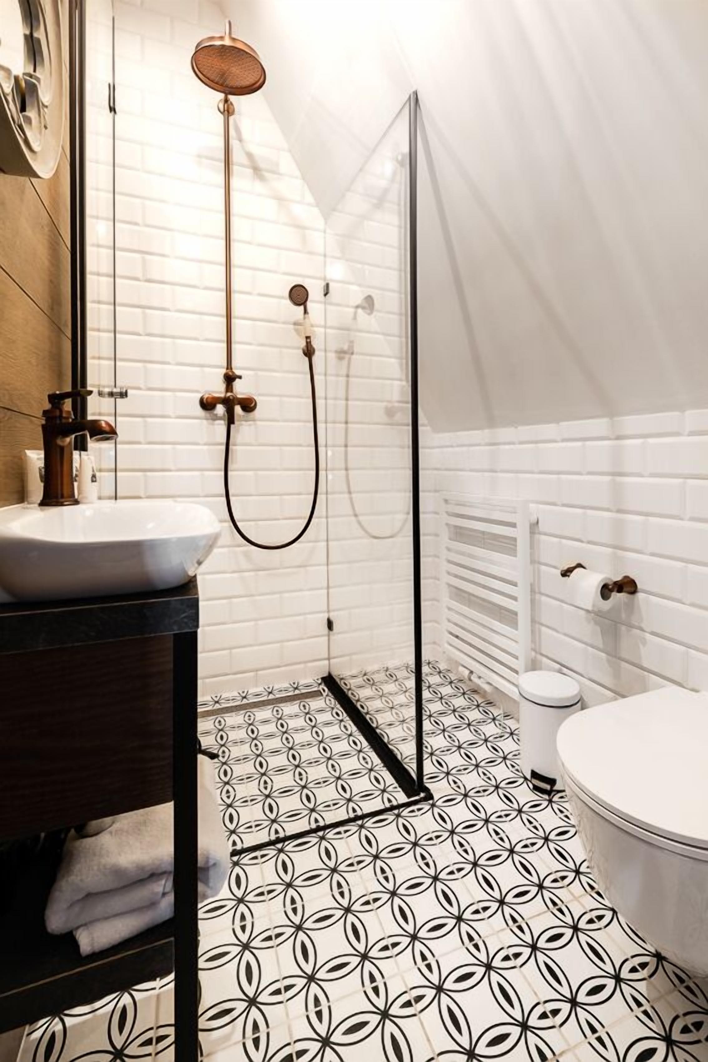 A modern bathroom with a white tiled shower, a sink with a dark countertop, and a toilet with a white lid.