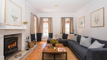 Una sala de estar con chimenea, un sofá gris oscuro y una mesa de centro.