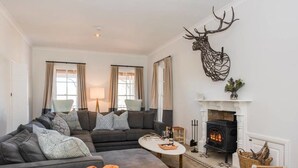 Una sala de estar acogedora con un sofá modular, una chimenea y una decoración de astas de ciervo.