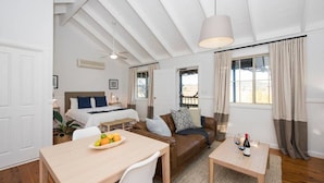 Una habitación con cama, sofá, una mesa de comedor con fruta y una mesita con copas de vino.