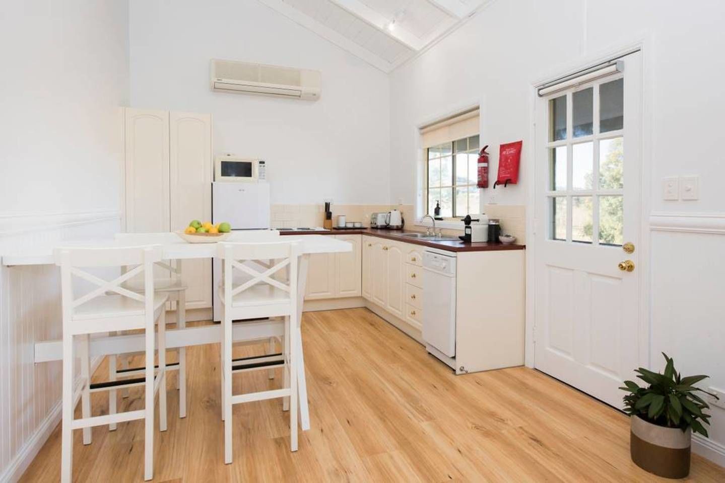 A kitchen with white cabinetry, a wooden countertop, and a white dining table with chairs.