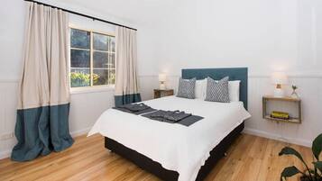 A bedroom with a bed, curtains, bedside tables, and a nightstand.