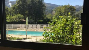 Une table dressée avec des aliments pour le petit-déjeuner, donnant sur une piscine et sur un espace verdoyant.