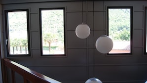 Une pièce dotée de trois fenêtres, d’une rambarde en bois et de luminaires suspendus.