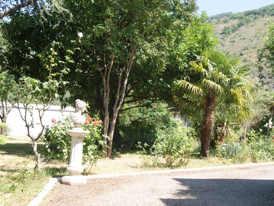 Un jardin agrémenté d’une statue, d’arbres et, au fond, d’une colline.