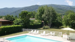 Une piscine dotée de chaises longues et offrant une vue sur une chaîne de montagnes.