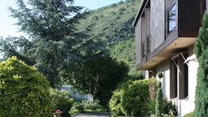 Une allée de gravier mène à un bâtiment dont l’extérieur est en bois, et on aperçoit un banc au premier plan.