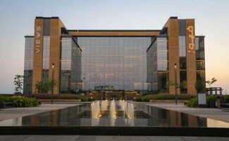 A modern building with a glass facade, labeled "VIEWS" and "GLOBE" on the sides. In front, there is a reflective water feature.