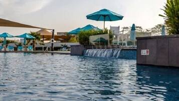 Relax by the serene pool, surrounded by lush greenery and a soothing waterfall.
