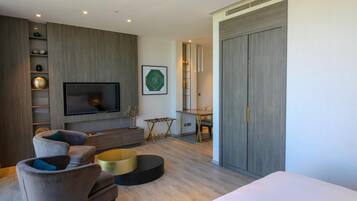 A modern bedroom with a large bed, a TV mounted on the wall, a desk, and a wardrobe.
