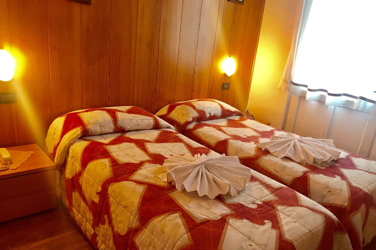 A double bed with a red and white quilt, two bedside tables, and a nightstand with a lamp.