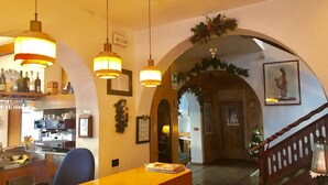 Een gezellige hotellobby met een houten receptiebalie, een koffieapparaat en hangende吊り下げ灯