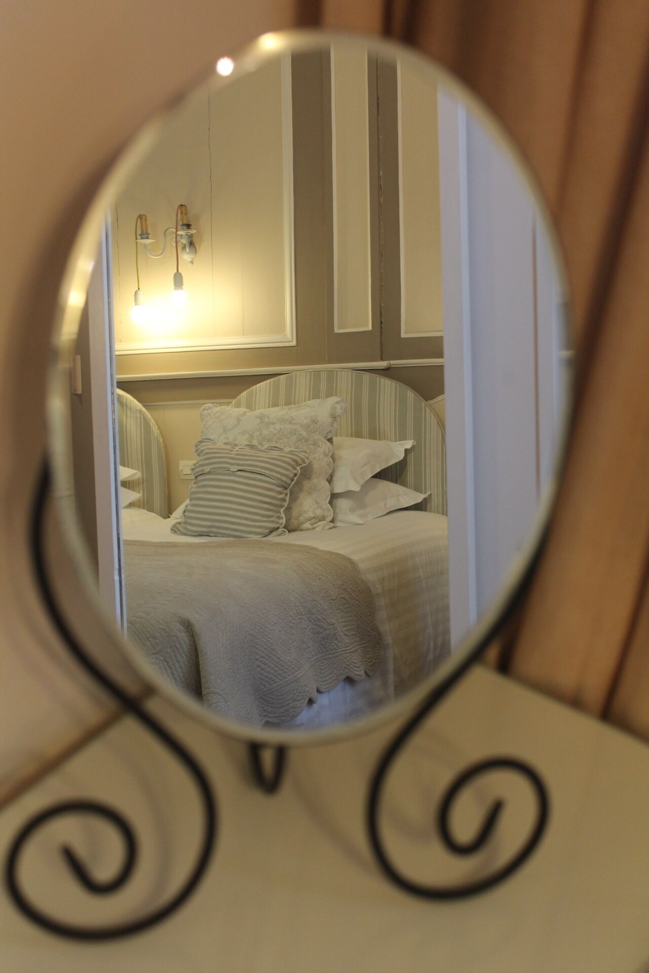 A bedroom with a bed, pillows, and a mirror on a stand.