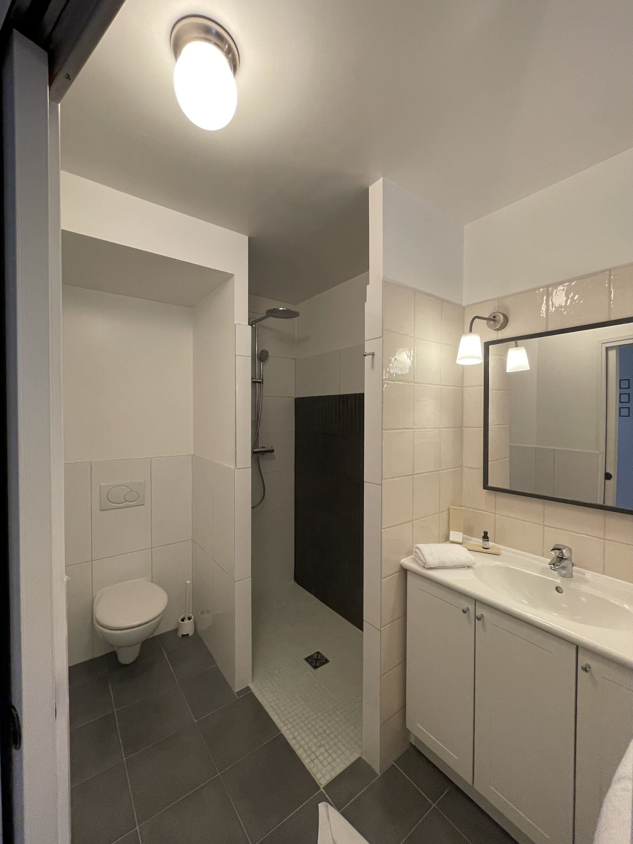 Et moderne badeværelse med toilet, bruser og håndvask.