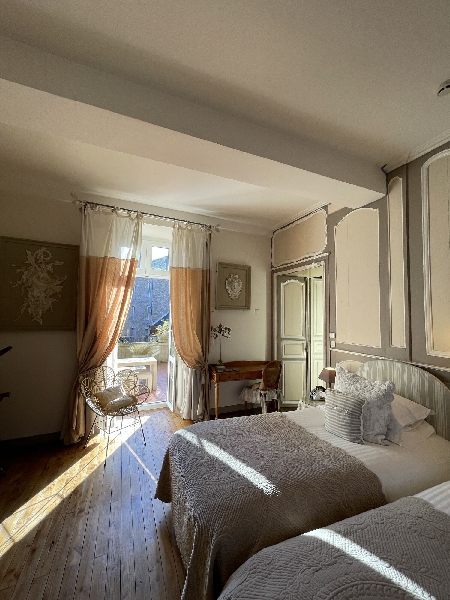 A bedroom with two beds, a desk, a chair, and a window with curtains.