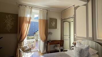 A bedroom with two beds, a desk, a chair, and a window with curtains.