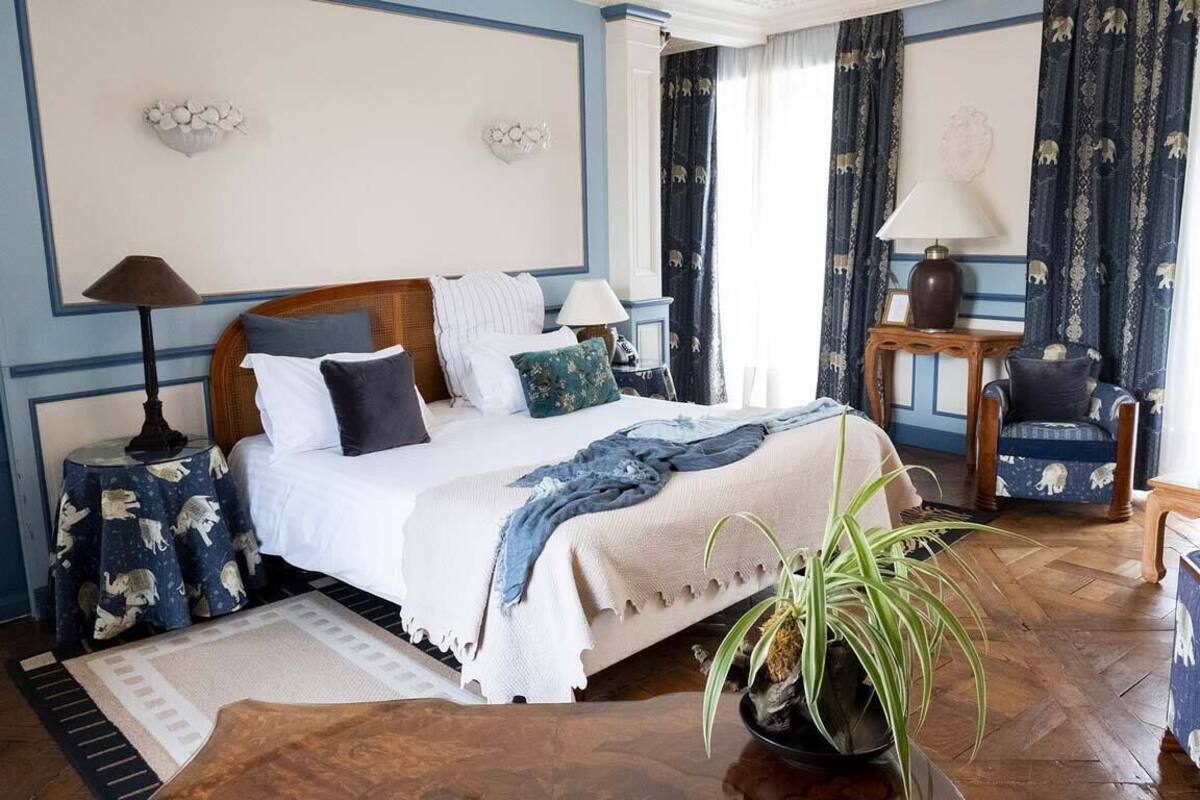 A well-appointed bedroom with a large bed, a side table, a chair, and a potted plant.