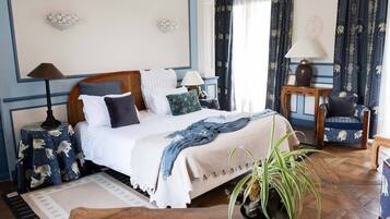 A well-appointed bedroom with a large bed, a side table, a chair, and a potted plant.