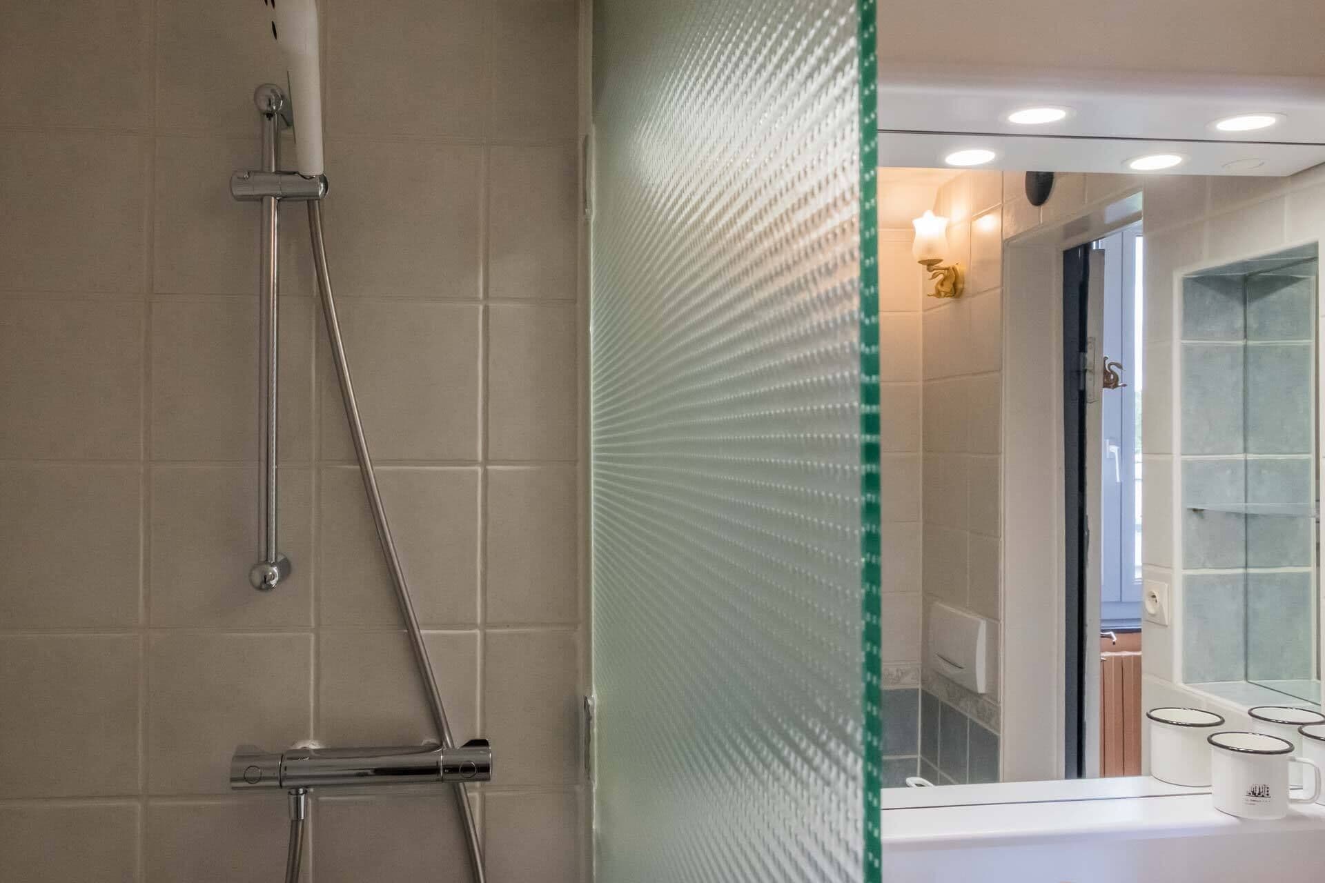 A modern bathroom with a glass shower enclosure, a visible toilet, and a sink area with a mirror.