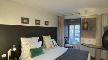 A neatly arranged bedroom with a bed, bedside table, lamp, and a window with curtains.