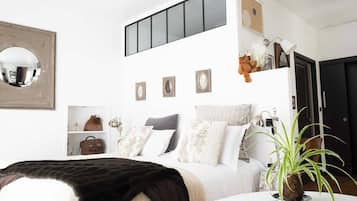 Un dormitorio con una cama, una mesita de noche con una planta, un espejo y una puerta.