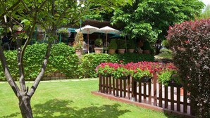 A garden with a wooden fence, potted plants, and a seating area with umbrellas. - Les Clos de Chaponost (Chaponost)