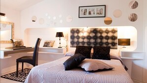 A modern bedroom with a tufted headboard, a desk with a chair, and a bed with patterned bedding. - Les Clos de Chaponost (Chaponost)