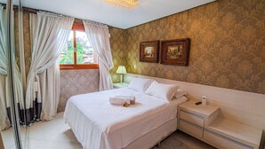 Une chambre à coucher avec un lit, une table de chevet, une lampe et deux tableaux encadrés accrochés au mur.
