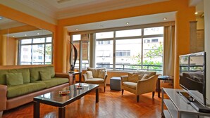 A spacious living room with a green sofa, a glass coffee table, and a beige armchair. - Rio Rentals 021 - T014 Apto de 3 quarto (Rio de Janeiro)