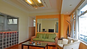 A living room with a wooden floor, a green sofa, a white sofa, and a coffee table. - Rio Rentals 021 - T014 Apto de 3 quarto (Rio de Janeiro)
