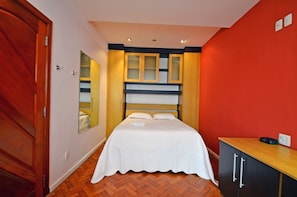 Ein Schlafzimmer mit Bett, Holzschrank und Spiegel.