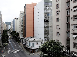 Une vue de rue avec des immeubles à plusieurs étages, un passage pour piétons et quelques personnes qui marchent.