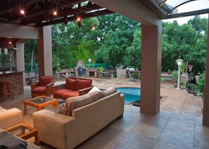 An outdoor patio area with a pool, seating, and a barbecue grill. - Paulshof Guesthouse (Sandton)