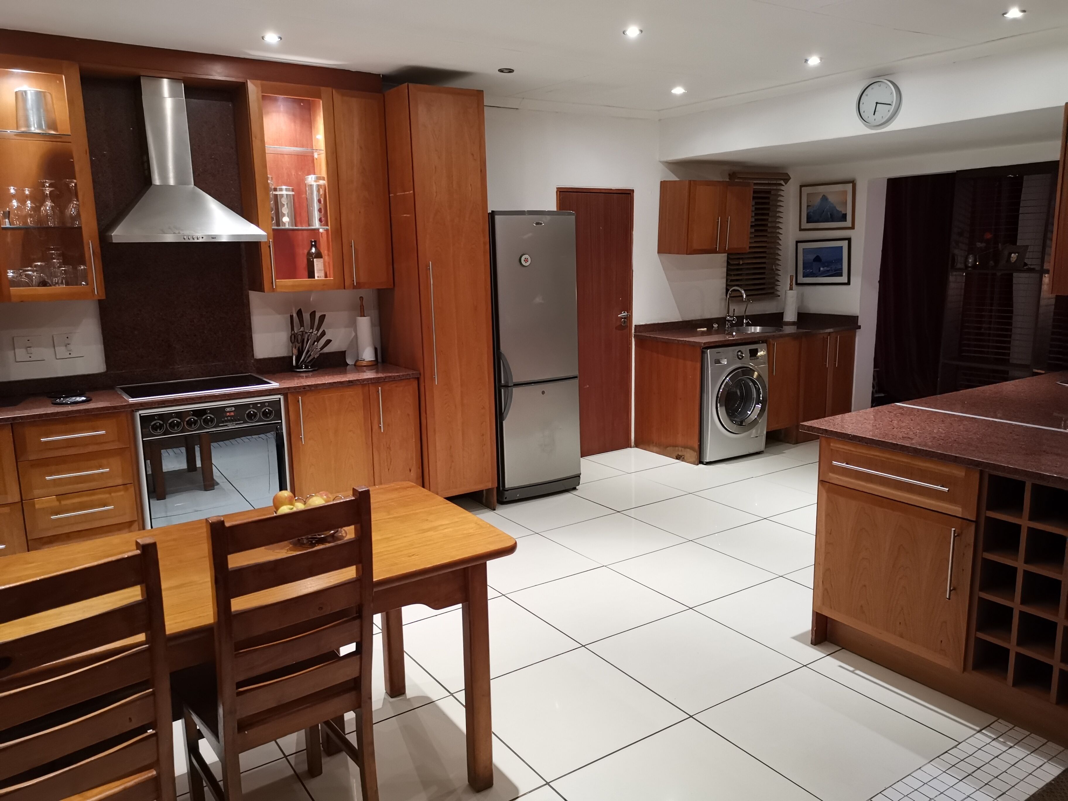 Una cocina moderna con armarios de madera, electrodomésticos de acero inoxidable y suelo de baldosas.