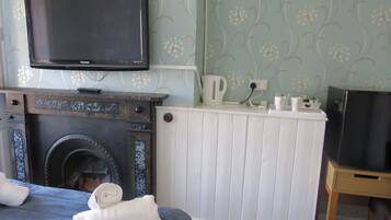 Una habitación con chimenea, televisor montado encima y una tetera, además de un radiador.