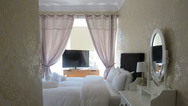 A hotel room with a bed, a desk, a television, and a mirror. - The Queens Arms Hotel (Hexham)