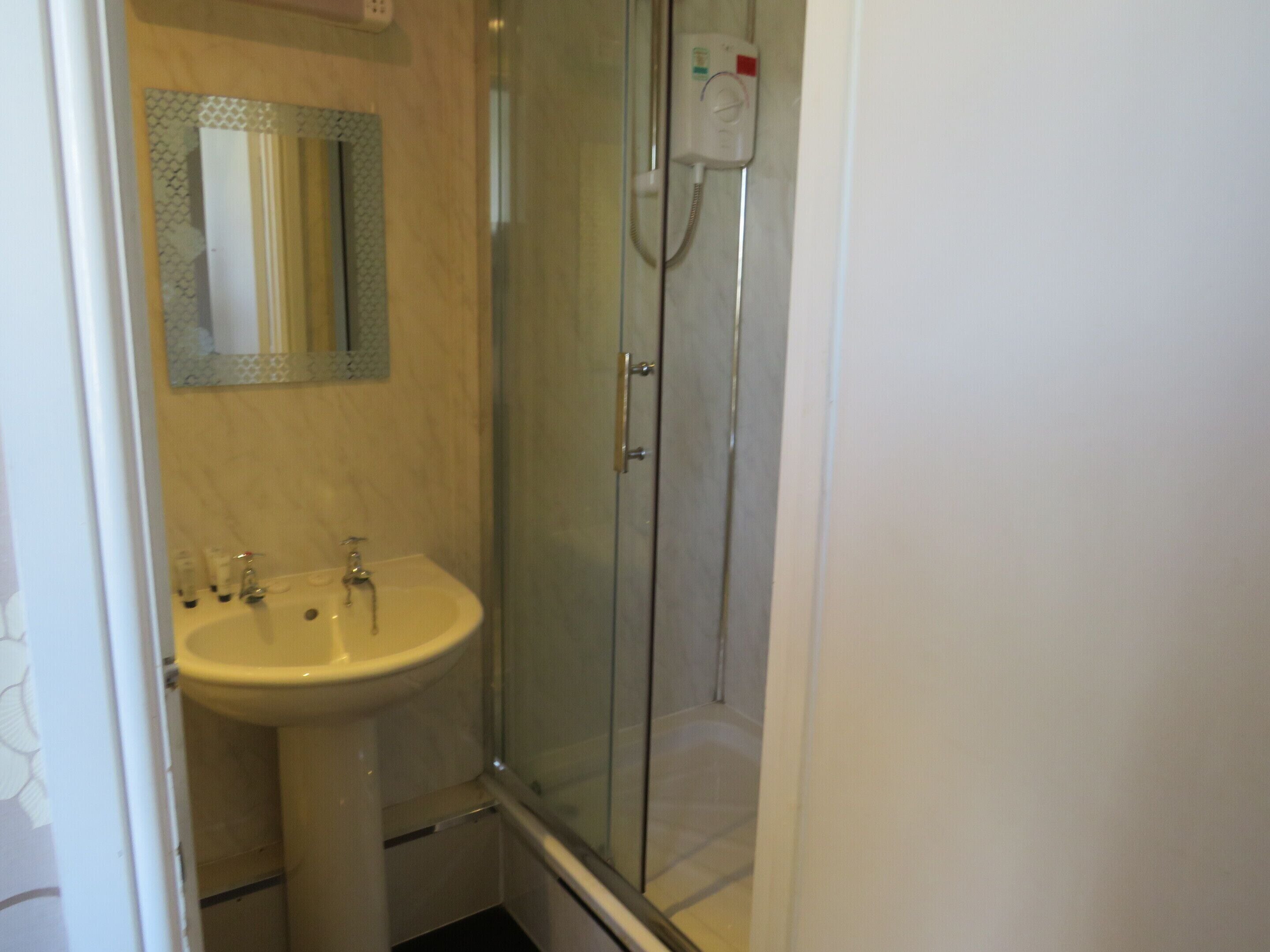 Un baño con ducha de vidrio, lavabo y espejo.