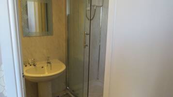 Un baño con ducha de vidrio, lavabo y espejo.