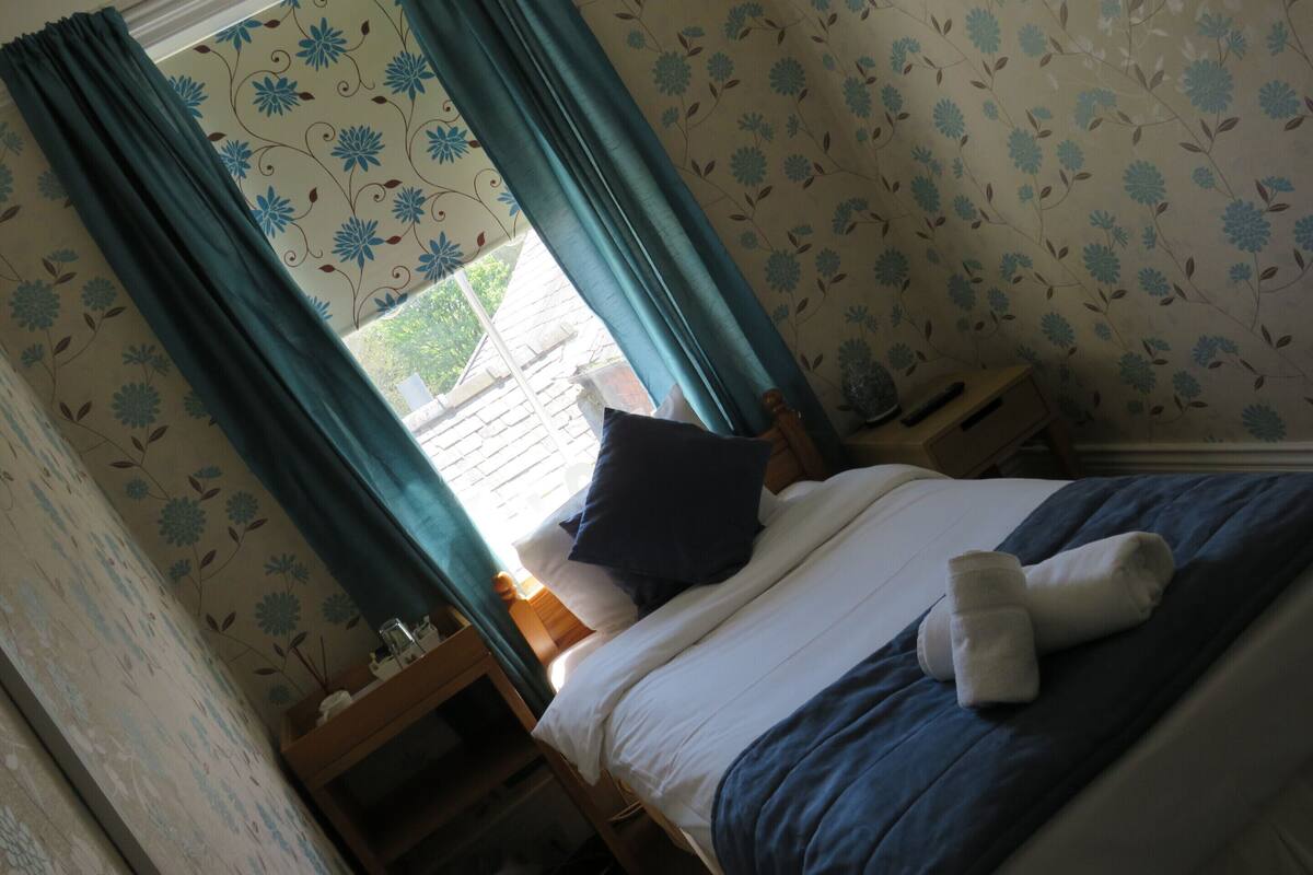 A bedroom with a bed, curtains, a bedside table, and a nightstand.