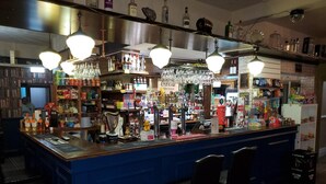 A bar area with a counter, stools, and various bottles and glasses. - The Queens Arms Hotel (Hexham)