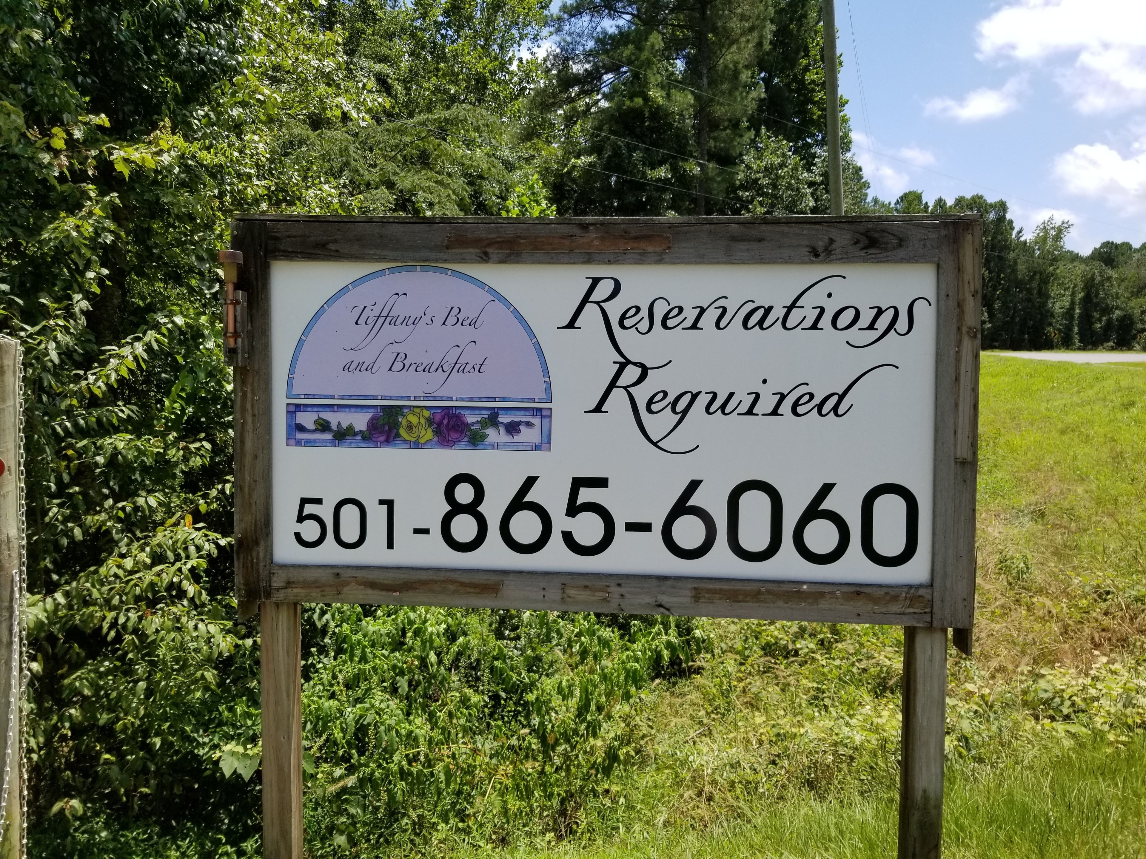 A sign for Tiffany's Bed and Breakfast stating reservations are required and providing a phone number.