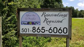 A sign for Tiffany's Bed and Breakfast stating reservations are required and providing a phone number.