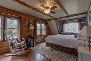 A bedroom with a bed, a rocking chair, a ceiling fan, and large windows. - Tiffanys Bed & Breakfast (Bismarck)