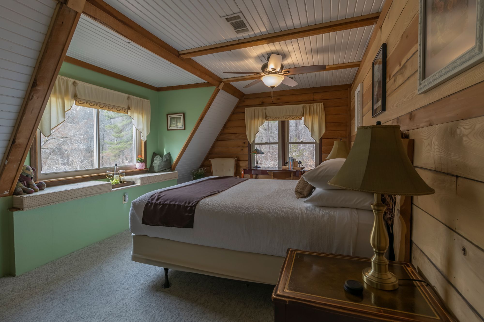 A bedroom with a bed, a nightstand, a lamp, and a ceiling fan.