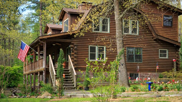 Eine rustikale Holzhütte mit Veranda, Flagge und Garten.