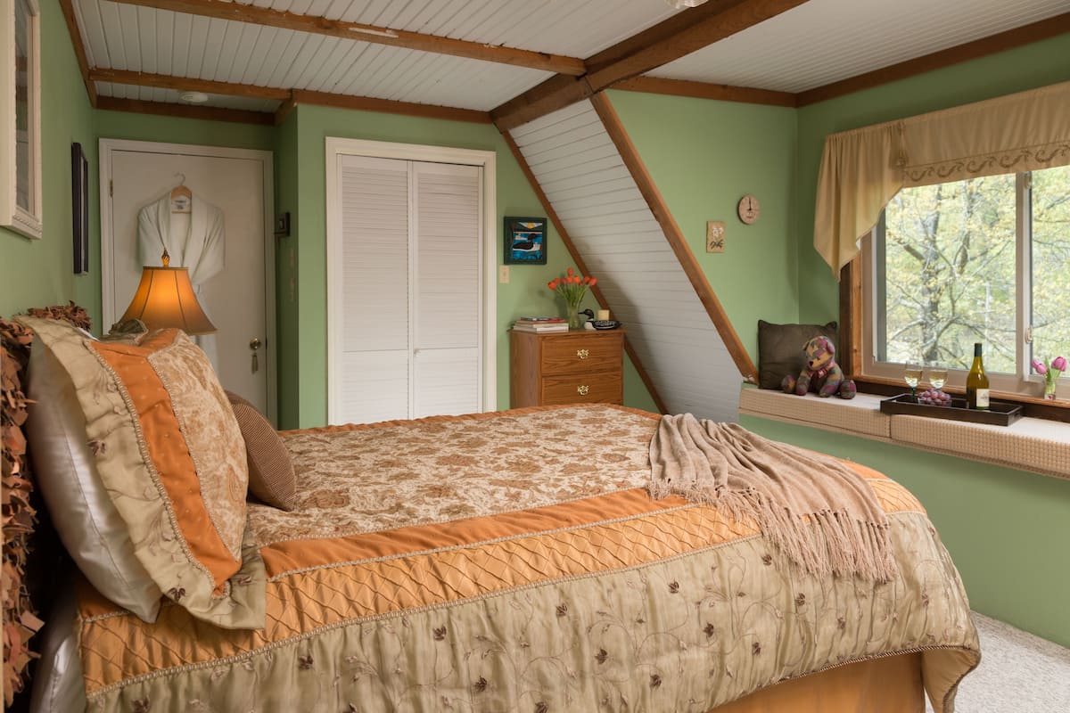 A bedroom with a bed, a window with a view, a dresser, and a lamp.