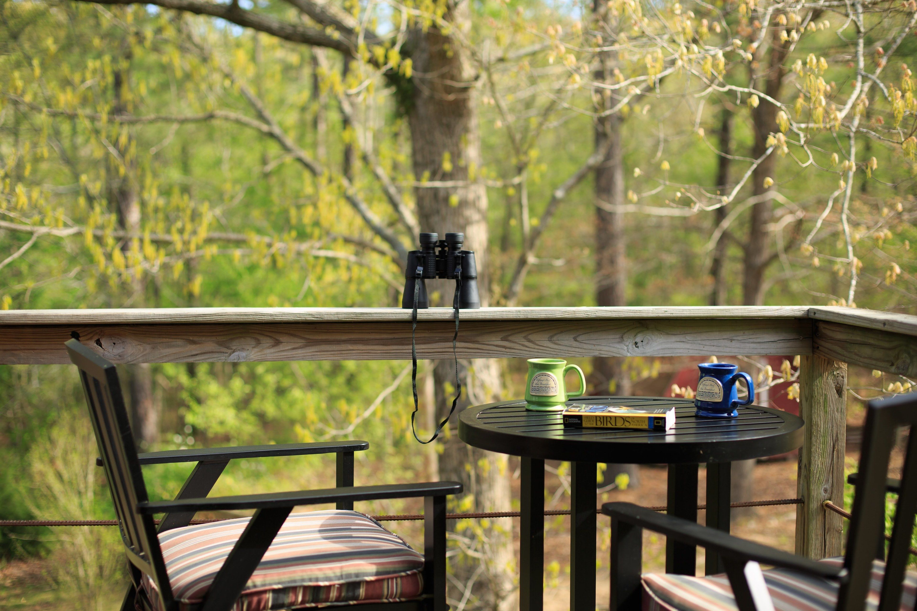 Une terrasse avec une table et des chaises, une paire de jumelles et un livre.