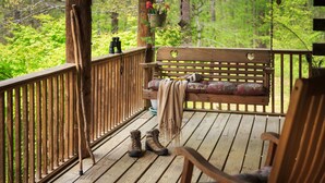 Eine Holzterrasse mit einer Bank und einem Stuhl, ein Paar Stiefel und Ferngläser.