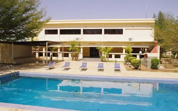 Una piscina al aire libre, sombrillas, sillones reclinables de piscina